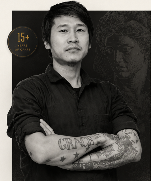 Xing, founder and tattoo artist, arms crossed with full sleeve tattoos